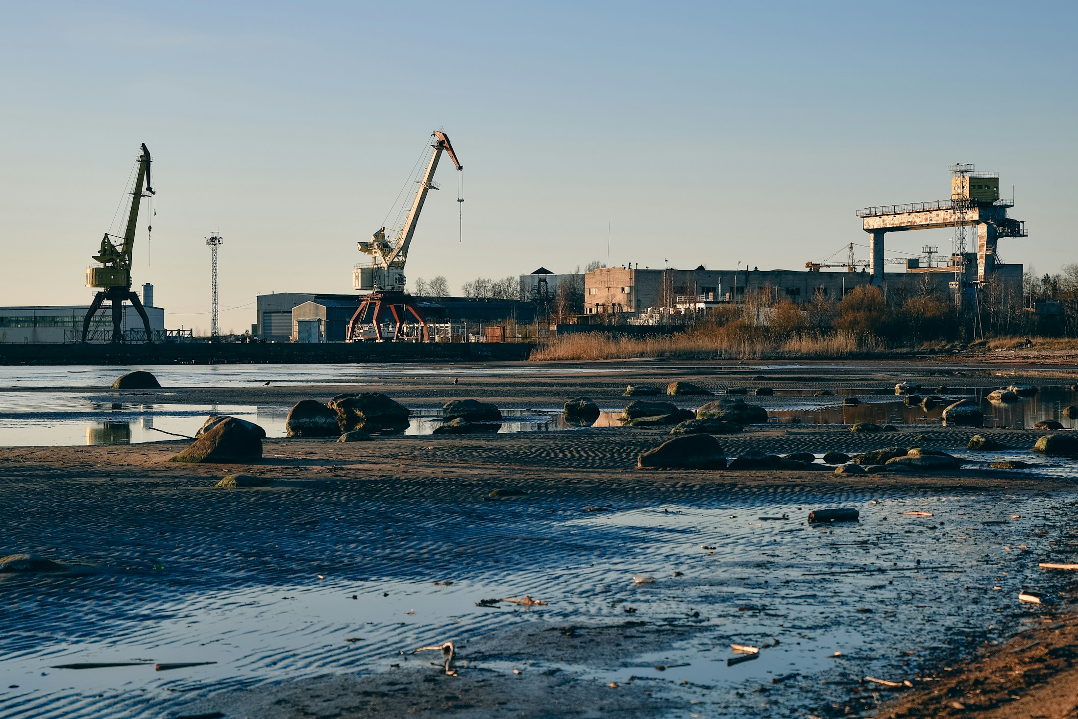 Foreign demand supports renewed growth in Estonian industry. Industrial cranes by the water with rocky shore